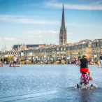 Cette photo met en avant une jeune fille en train de faire de vélo à roulettes sur le miroir d'eau. 