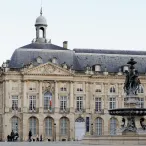 Cette photo met en avant la place de la Bourse. La fontaine des Trois Grâces est présente sur la photographie également.