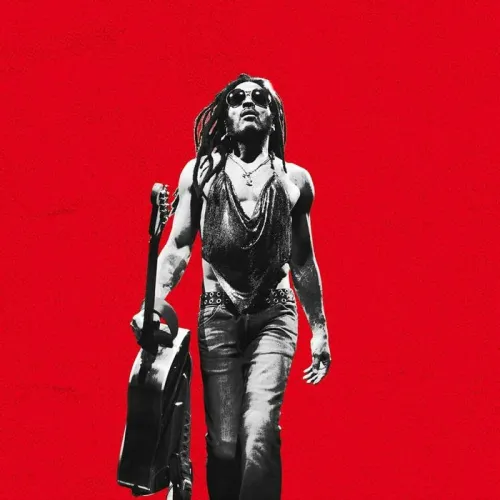 Lenny Kravitz performing at Arkéa Arena in Bordeaux, wearing sunglasses and holding a guitar against a bright red background.