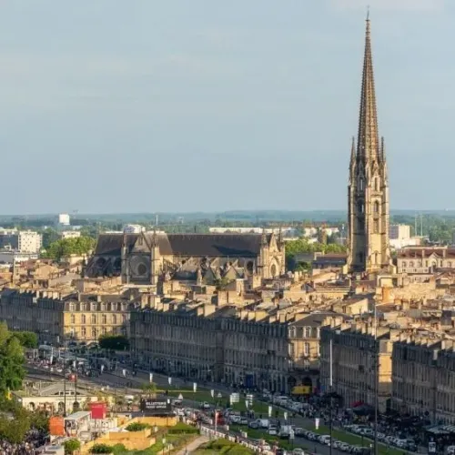 Aerial view of Bordeaux showcasing the Saint-Michel Spire dominating the historic city center with its stone buildings and mansard roofs.