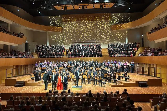 Viva Vivaldi symphonic choir performance in Bordeaux concert hall featuring full orchestra and singers on stage with audience in balconies and seating area.