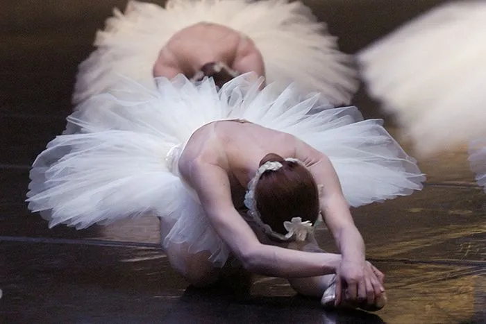 Ballet dancer in white tutu performing a bent-over pose on stage during a Swan Lake performance in Bordeaux