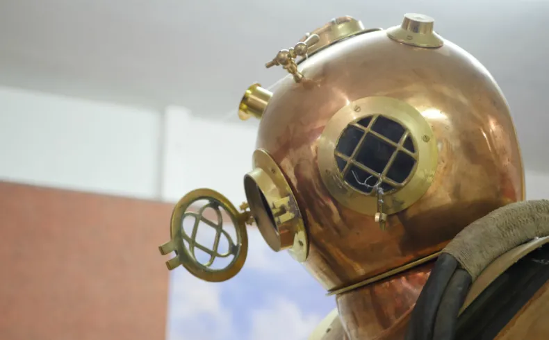 Vintage copper and brass diving helmet with gridded portholes, displayed at the Museum of Friends of Old Lormont in Bordeaux