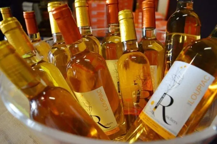 Display of golden and amber-colored Loupiac white wine bottles arranged for tasting in Bordeaux