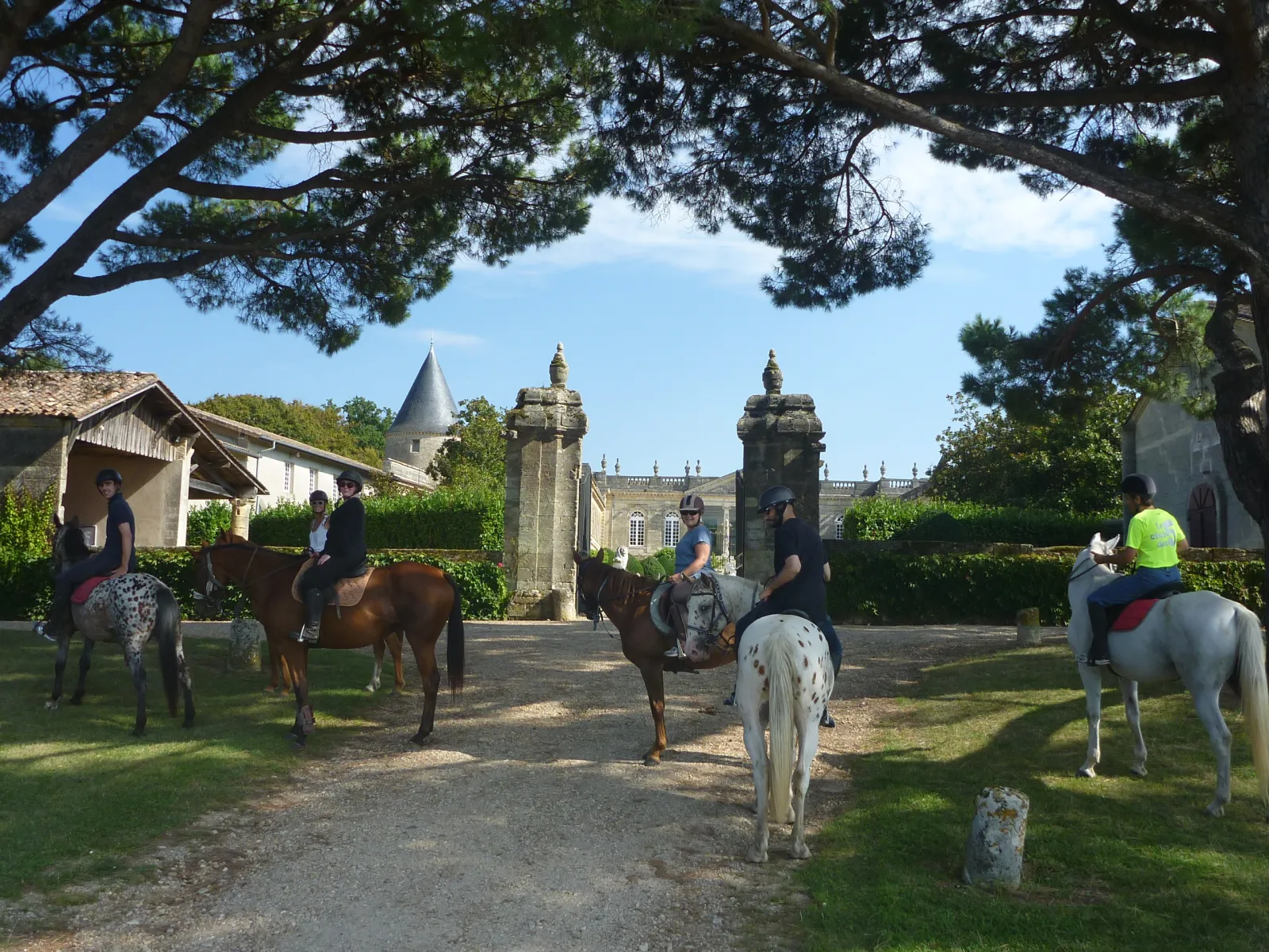 Horseback riders gathered in front of Château Saint-Georges in Bordeaux, featuring distinctive towers and a tree-lined approach