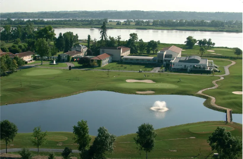 Aerial view of Golf de Margaux near Bordeaux, featuring manicured greens, water hazards, and clubhouse buildings overlooking the Gironde river