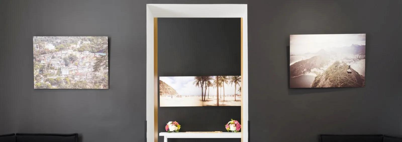 Wall gallery at Saint-James Bordeaux displaying three landscape photographs and a central bay window with palm tree image, decorated with colorful flowers