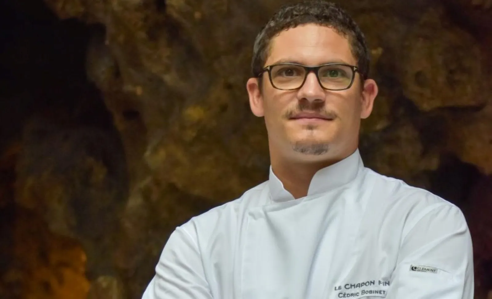 Portrait of Cédric Bobinet, head chef at Le Chapon Fin restaurant in Bordeaux, wearing a white chef's jacket and glasses