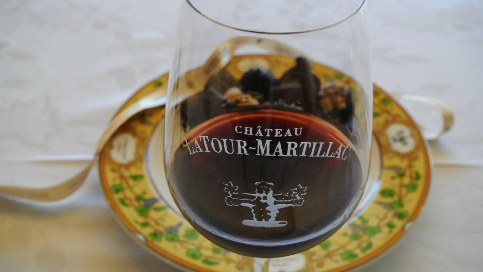Glass of red wine from Château Latour-Martillac Bordeaux, served on a decorative plate with gold and green patterns