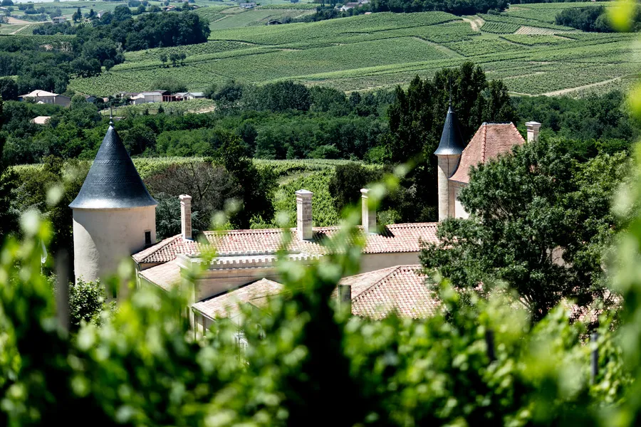 Aerial view of Château Toulouse-Lautrec near Bordeaux, featuring distinctive conical towers, terracotta roofs, and surrounding vineyards in the Gironde countryside.