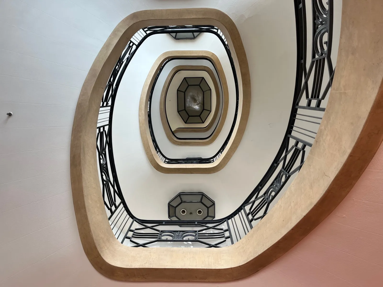 Overhead view of an octagonal stairwell with ornamental black and white railing in Galeries Lafayette Bordeaux