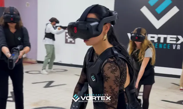 A woman wearing a VR headset at Vortex Experience VR venue in Bordeaux, surrounded by other participants in an immersive experience space