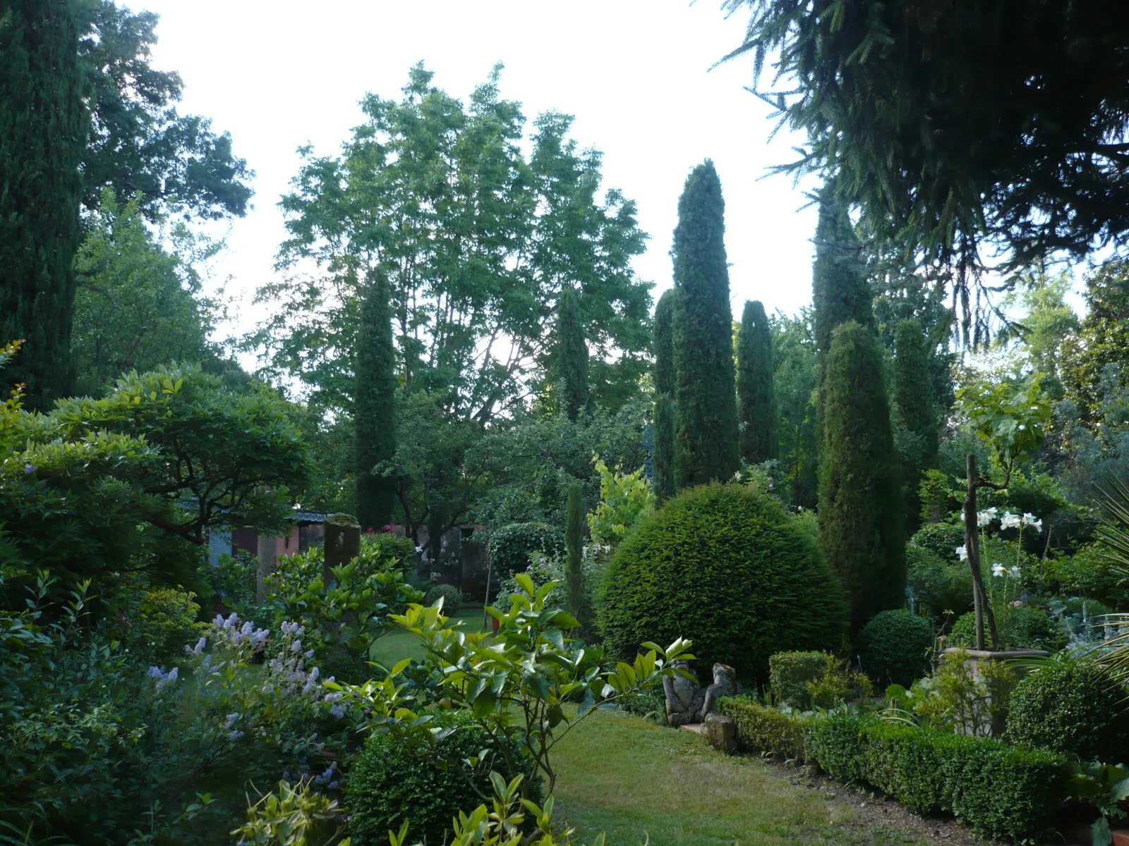 View of Jardin du Clozet in Bordeaux featuring a central pathway lined with tall cypress trees and lush greenery