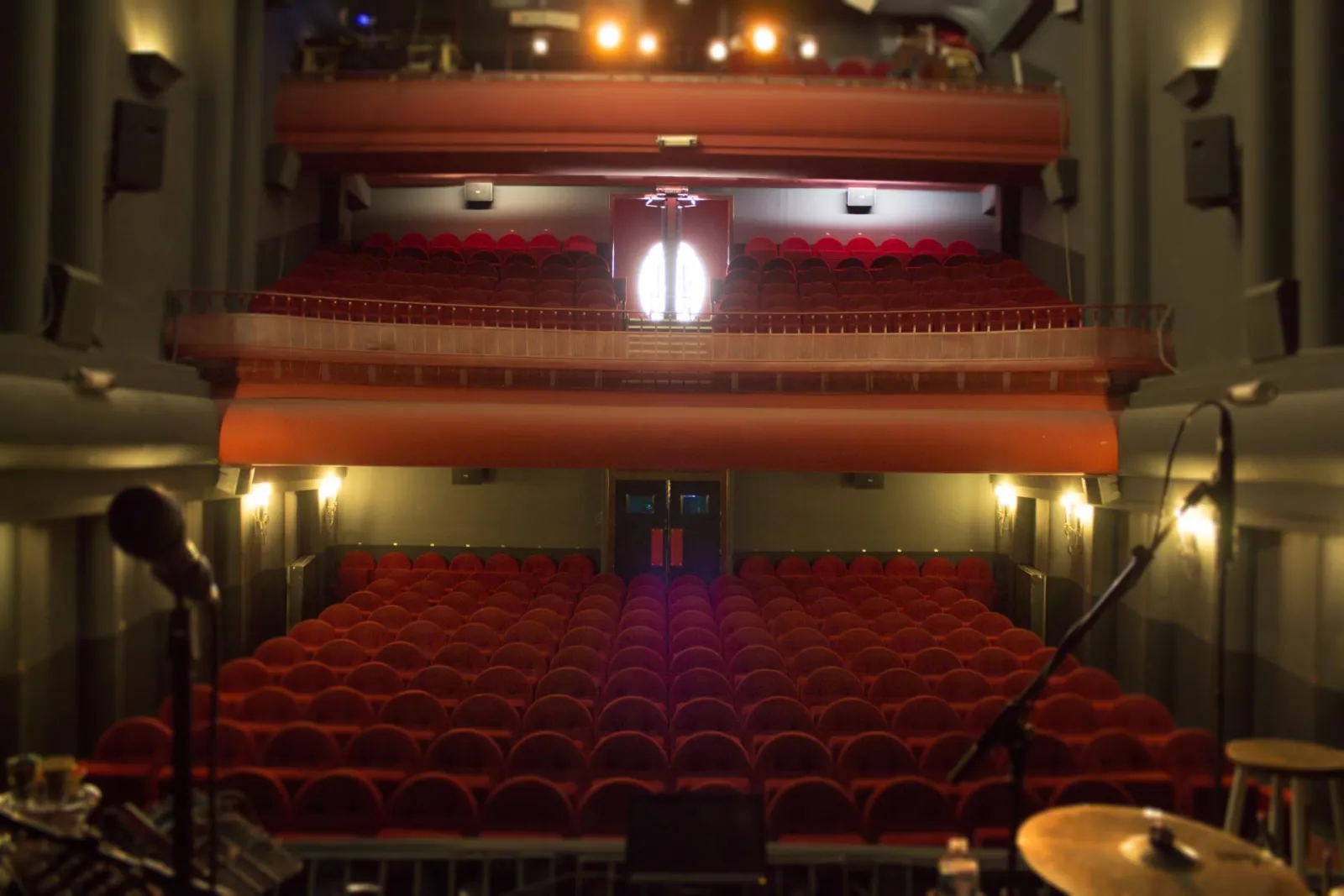 Interior of Bordeaux's Trianon Theatre featuring empty red velvet seats, upper balcony level, and stage lighting