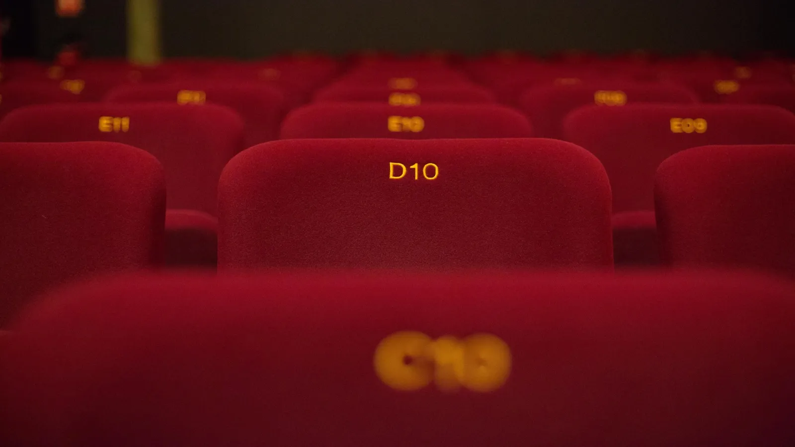 Cinema theater with red numbered seats D10 and two drinks in the foreground