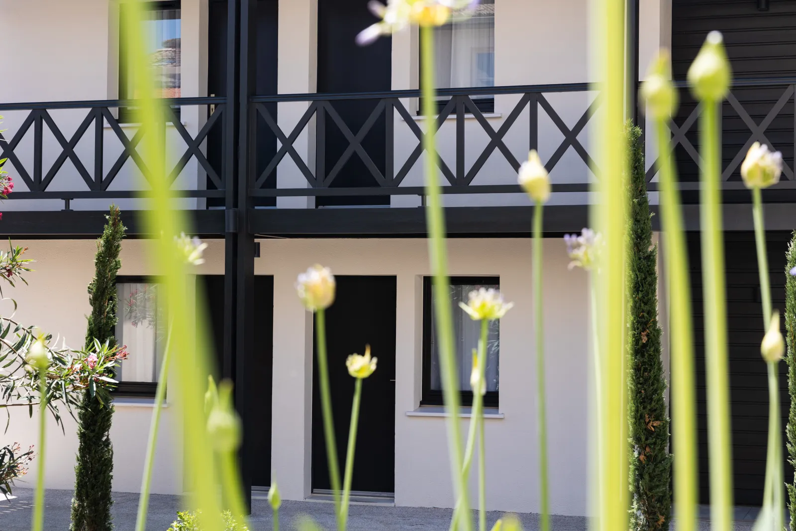 Elegant facade of the Best Western Premier Hôtel Des Vignes Et Des Anges in Bordeaux, featuring yellow flowers in the foreground and an ornamental black balustrade