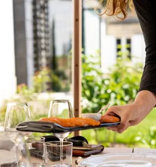 Person pouring red wine into a glass during a tasting at Chais de la Fleur in Bordeaux, with vineyard view in the background