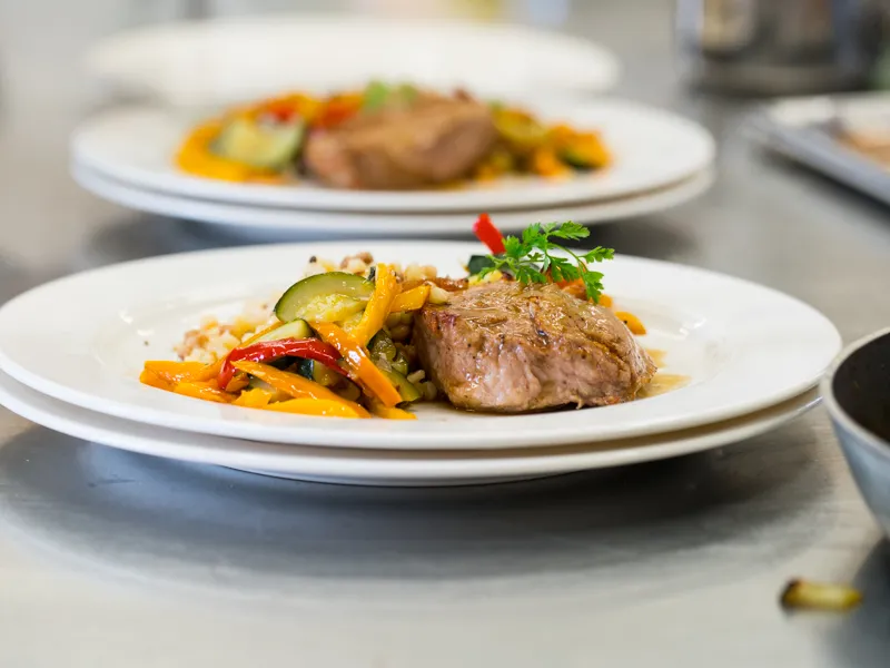 Grilled meat plate with sautéed colorful vegetables and fresh herbs, presented at a cooking workshop at Château Kirwan in Bordeaux