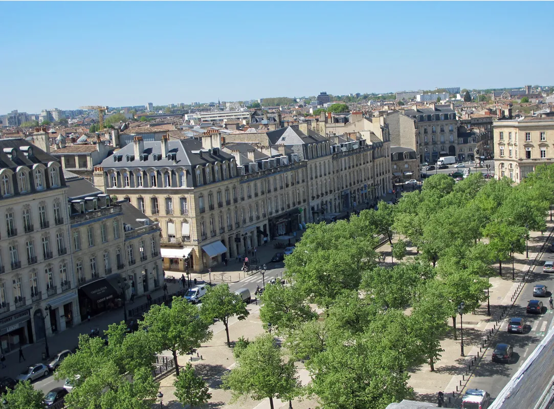 Aerial view of Allées de Tourny in Bordeaux featuring Haussmann-style buildings, green trees, and stone facades.