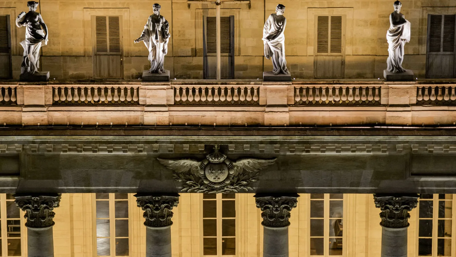 Neoclassical facade of the Grand Theatre of Bordeaux featuring Corinthian columns, white statues on the upper terrace, and a central winged crown relief