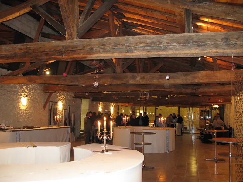 Interior of the Maison des Vins de Graves in Bordeaux featuring exposed wooden beams, white tasting counters, and chandelier with visitors in the background