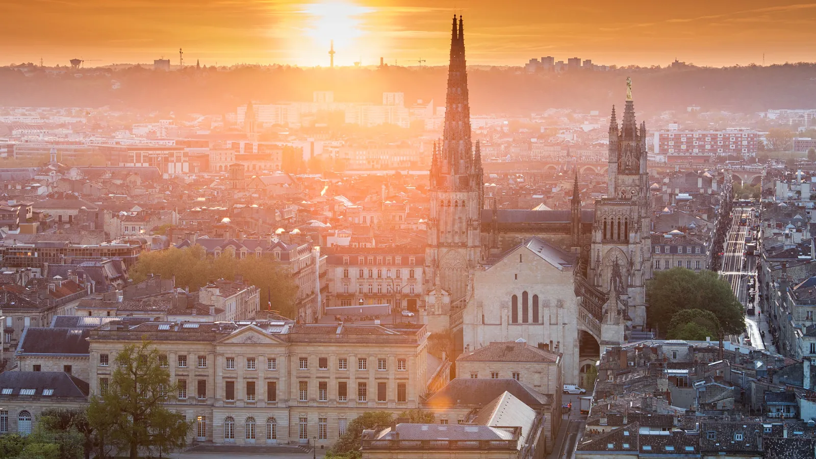 Aerial view of Bordeaux at sunset featuring the Saint-André Cathedral with its two Gothic towers overlooking the historic city center
