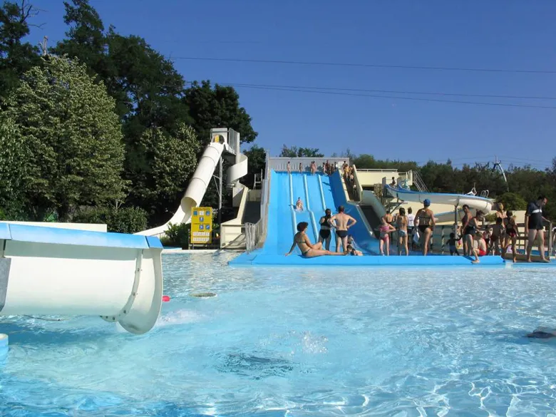 Water park at Pessac Nautical Stadium in Bordeaux featuring a blue water slide, swimming pool, and visitors enjoying a sunny day.