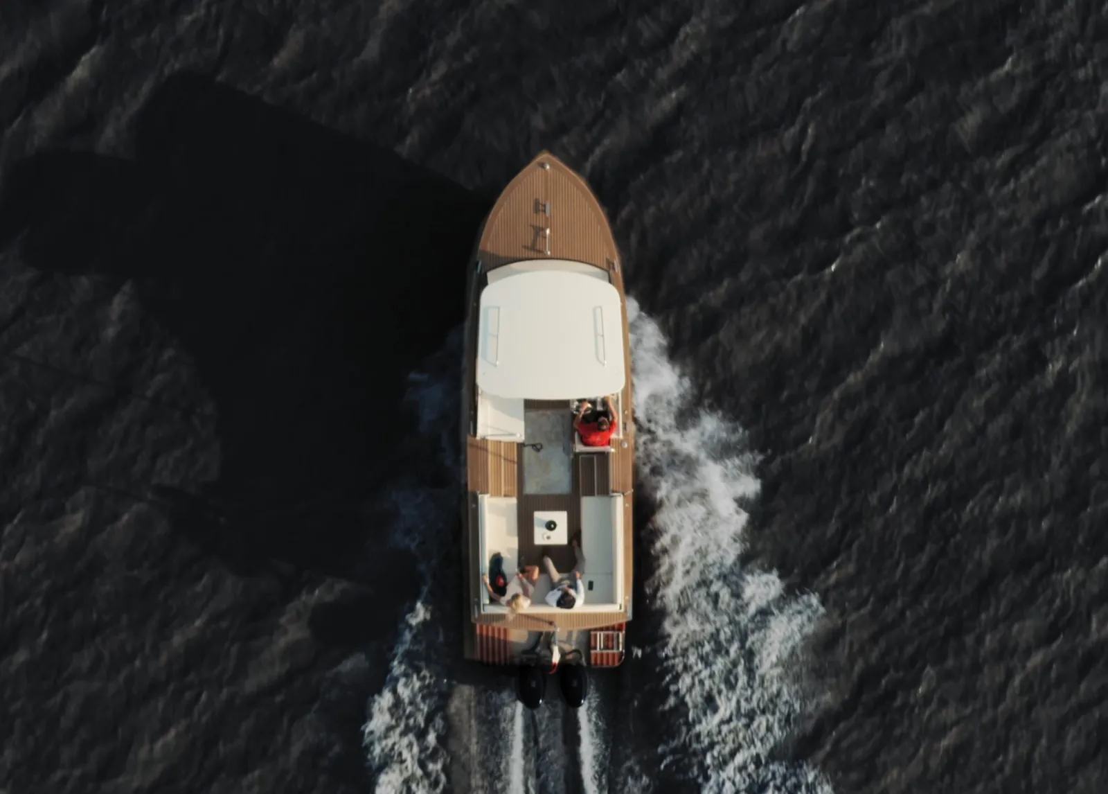 Aerial view of the Grattequina water taxi boat cruising on the Garonne River in Bordeaux, with wake waves visible on both sides