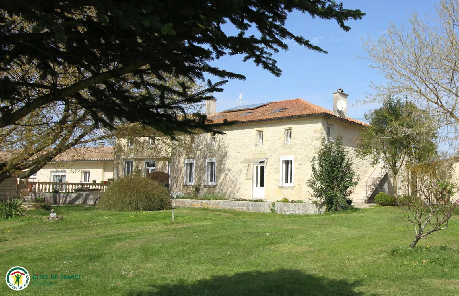 Pierre de Montignac Castle, a white stone guesthouse with tiled roof surrounded by lush gardens and trees near Bordeaux.