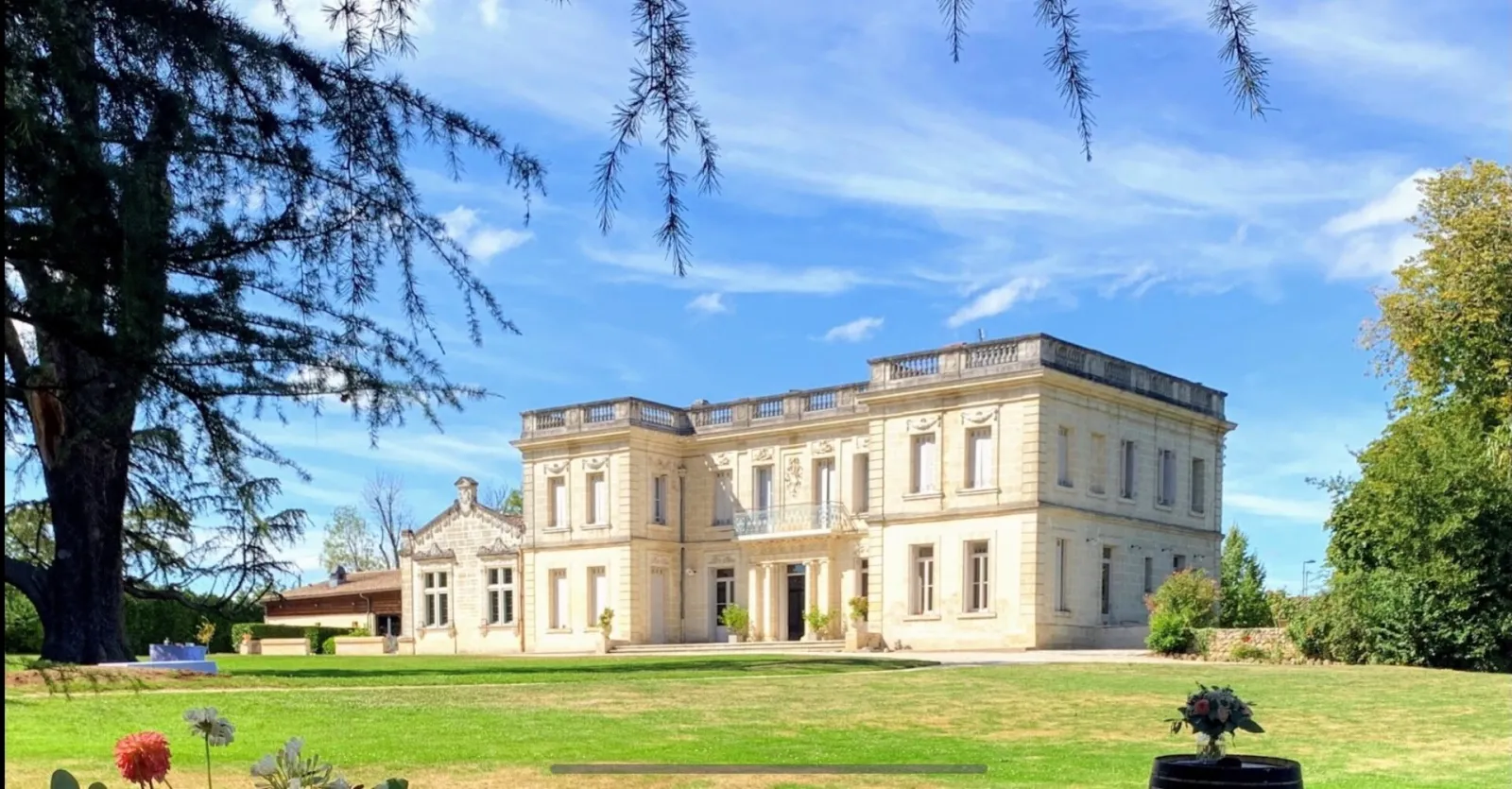 Château La Chèze in Bordeaux, a neoclassical stone mansion with symmetrical facade, situated in a lush green park surrounded by ancient trees