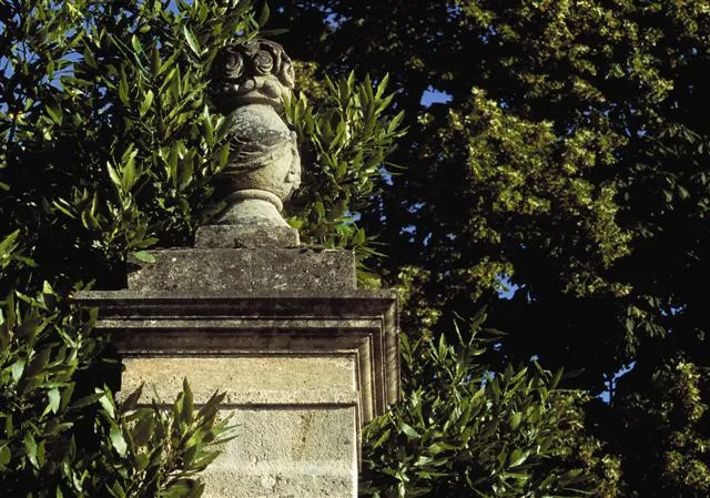 Stone bust on a decorative pedestal surrounded by green foliage at Château La Haye in Bordeaux