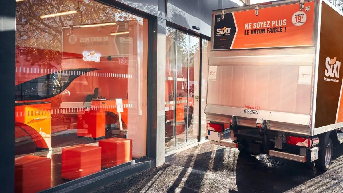 SIXT car rental agency in Bordeaux featuring a modern red and orange storefront with a white and red rental truck parked in front of the glass entrance.