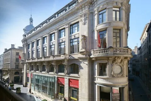 Ornate facade of the Galeries Lafayette building in Bordeaux, Beaux-Arts architecture with balconies and balustrades, French flags visible