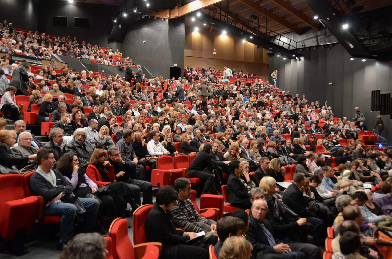 A modern cinema hall filled with hundreds of spectators seated in red armchairs during a screening or event at Pin Galant in Bordeaux.
