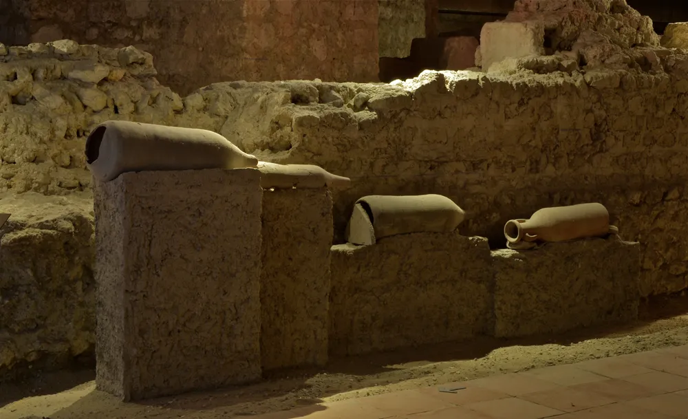 Archaeological remains from the Saint-Seurin site in Bordeaux: ancient pottery and ceramic fragments displayed on stone blocks in an underground excavation.