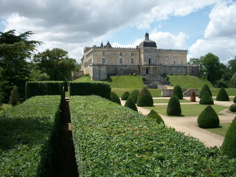 Château de Vayres castle with towers and crenellations, surrounded by formal French gardens with trimmed boxwood hedges and topiary, near Bordeaux.