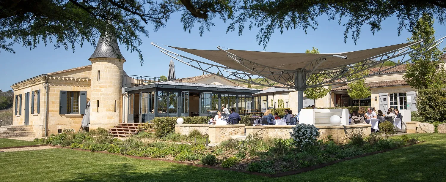 Exterior view of Atelier de Candale in Bordeaux featuring stone buildings, covered terrace, landscaped garden and visitors