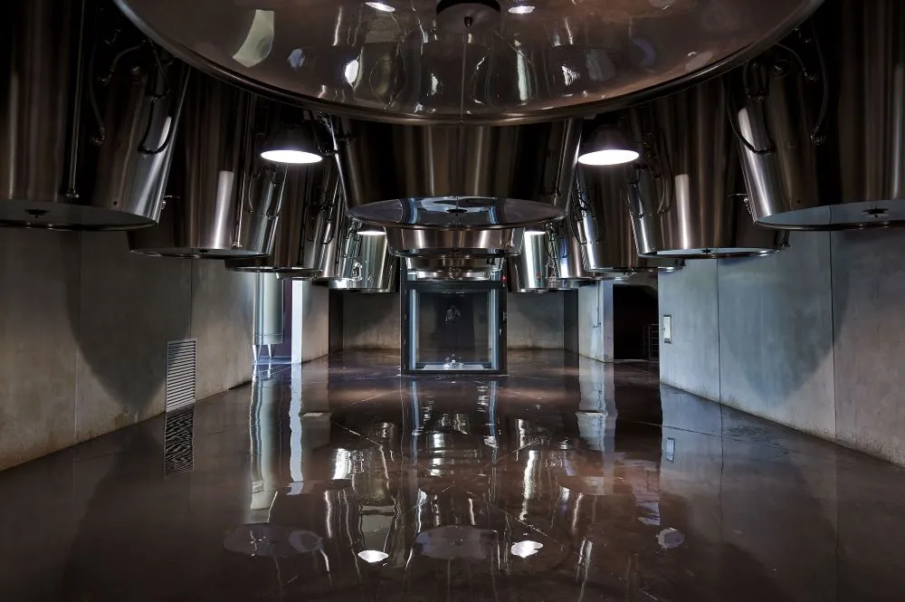 Modern winery interior featuring stainless steel fermentation tanks, reflective floor and LED lighting at Château La Fleur de Boüard in Bordeaux.