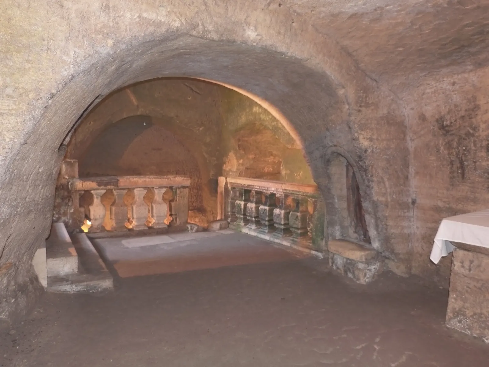 Interior view of a vaulted gallery in Château Laniote in Bordeaux, featuring ancient stone walls, brick arches, and stone balustrades illuminated by natural light.