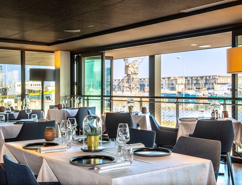 Elegant dining room at Wellman Restaurant & Bar in Bordeaux featuring set tables, panoramic windows overlooking the city and river port