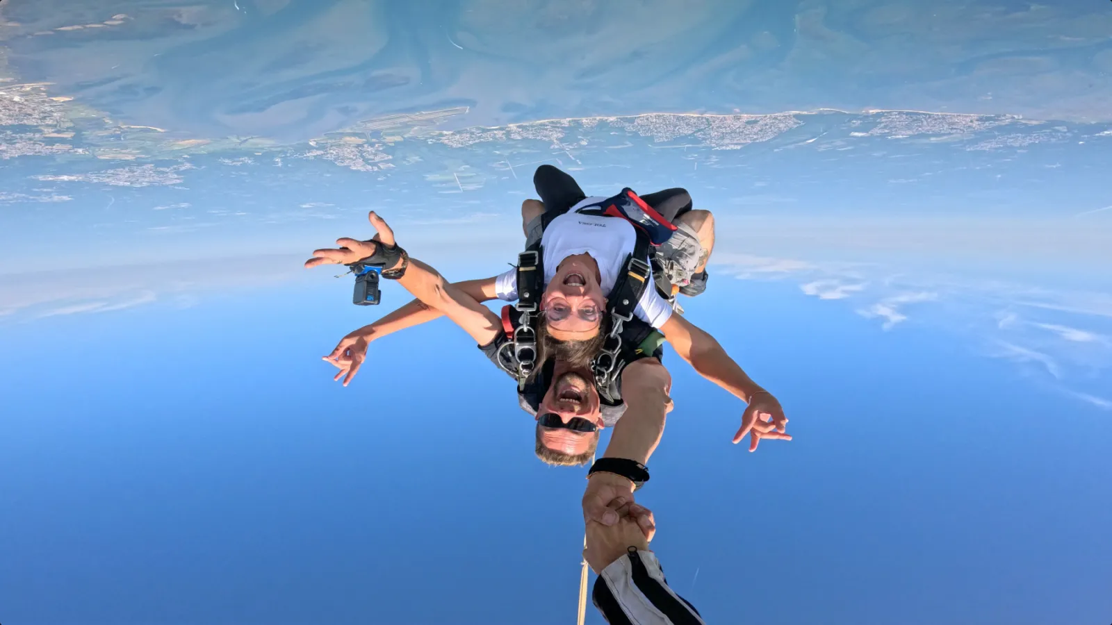 Two skydivers in freefall above Bordeaux, aerial view with blue sky and landscape above