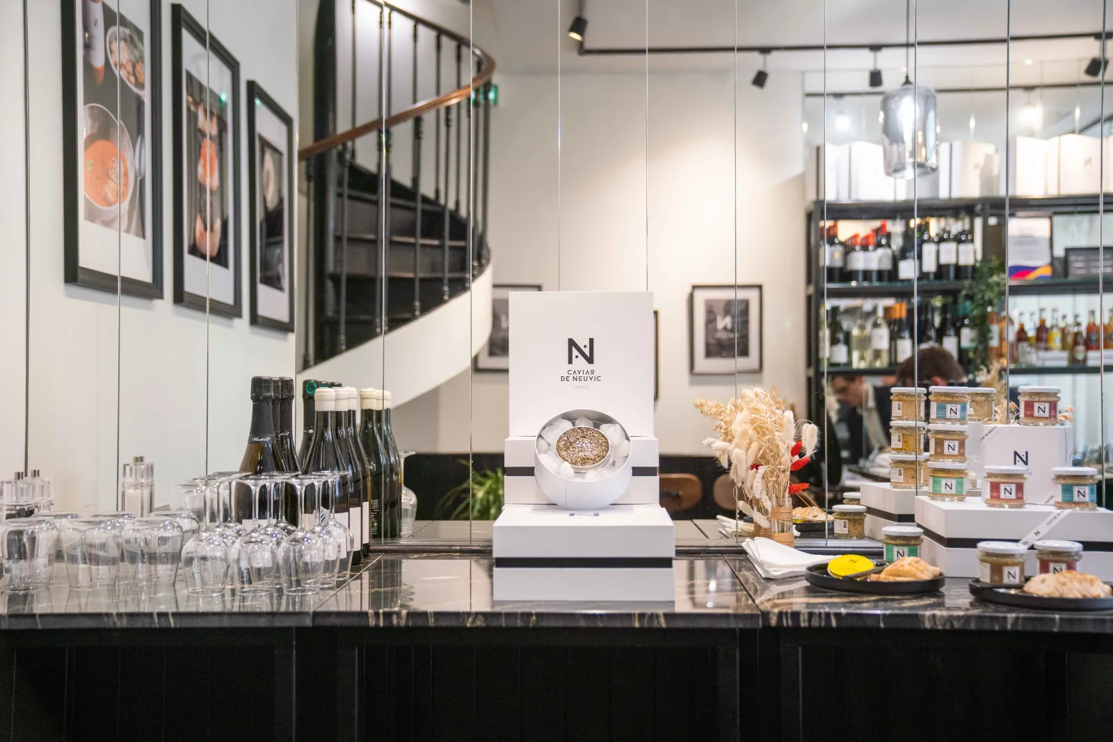 Caviar de Neuvic showcase counter in Bordeaux displaying premium caviar, champagne bottles, glasses, and luxury gourmet products in an elegant setting