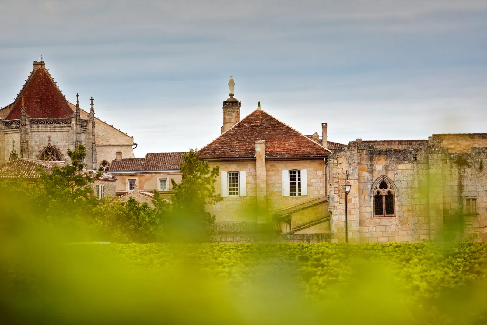 View of the Jacobins Convent in Bordeaux featuring Gothic stone and brick buildings surrounded by lush greenery