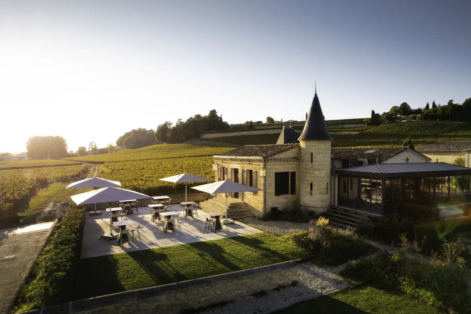 Aerial view of Candale château featuring shaded terrace, surrounding vineyards and elegant architecture near Bordeaux