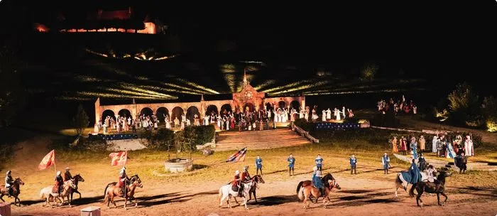 Night-time performance of the Battle of Castillon near Bordeaux featuring mounted horsemen, audience in background, and illuminated architectural structures