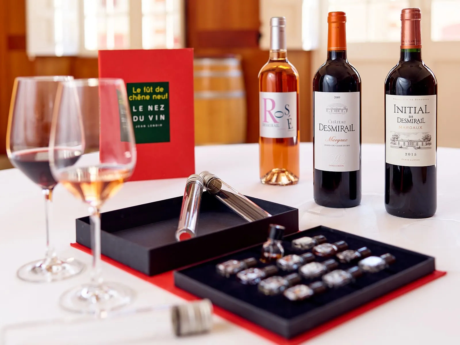 Wine tasting display from Château Desmirail in Bordeaux featuring red and rosé wine glasses, Margaux and Initial Desmirail bottles, fine chocolates and tasting accessories on white table