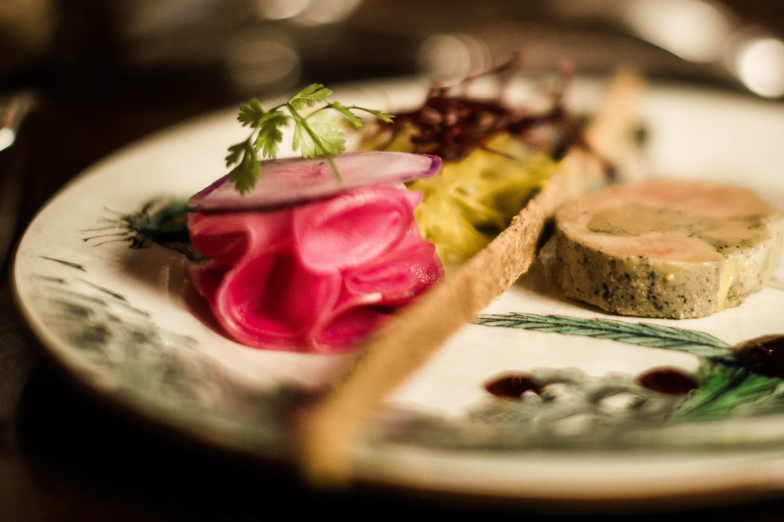 Gourmet plate from La Table de Siaurac in Bordeaux featuring sliced foie gras, colorful vegetables, and aromatic herbs on sauce, garnished with parmesan and chives