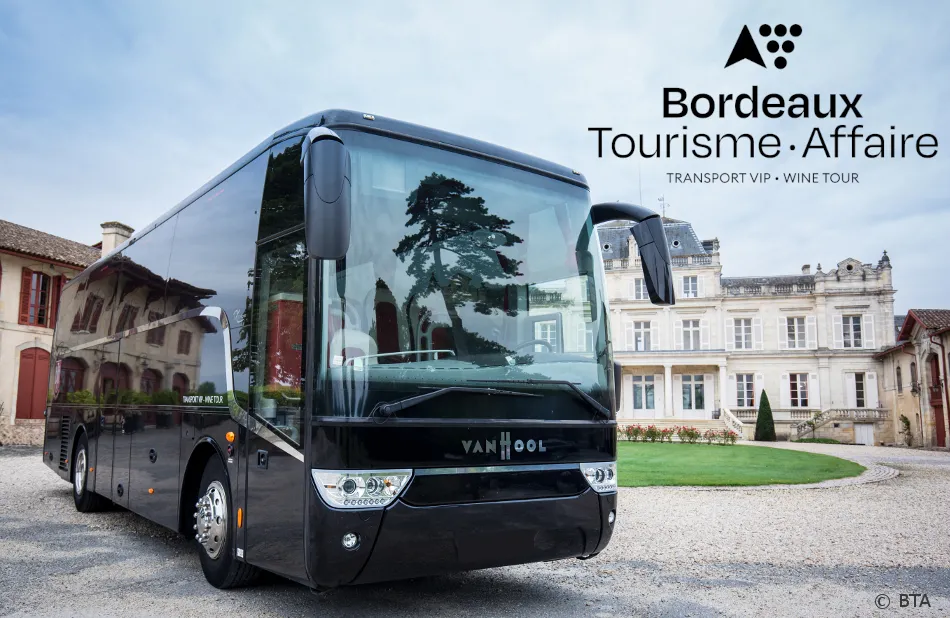 Black VanHool coach bus from BTA parked in front of a Bordeaux castle with historic buildings in the background, offering VIP transport and wine tour services.