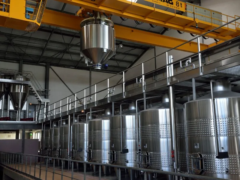 Modern winemaking facility with stainless steel vats and yellow overhead crane in a Saint-Émilion cellar