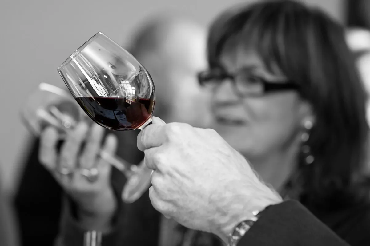 Woman holding a glass of red wine in Bordeaux, examining the color and clarity during wine tasting